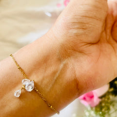 Gold bracelet with clear gemstones on a wrist against a blurred background